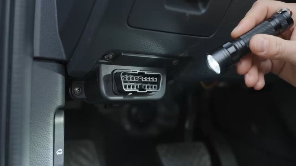 Toma OBD2 de 16 pines ubicada debajo del volante en un vehículo